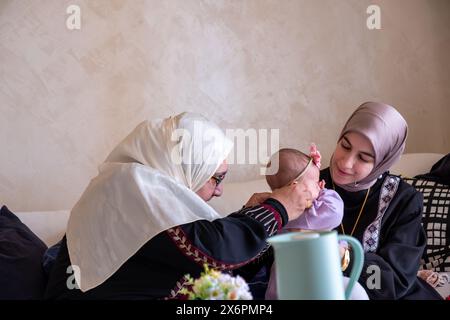 Mother and grandmother are playing with baby wearing beautiful clothes celebrating and enjoying their moments with children Stock Photo