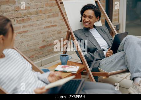 Two young female colleagues working on new project while sitting at office terrace Stock Photo