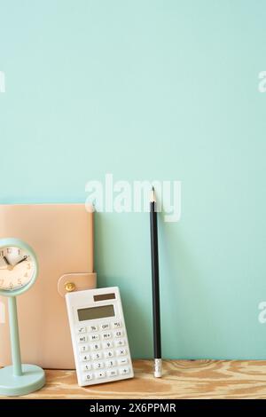Workspace diary note, calculator, pencil, clock on wooden desk. mint wall background Stock Photo