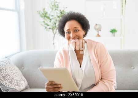 Black woman using tablet on living room at home Stock Photo