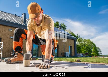 Worker leveling concrete tiles on construction site. Building patio floor. Stock Photo