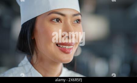 World Famous Restaurant: Portrait of Smiling Asian Female Chef Cooking Delicious, Steamy, Authentic Food, Happy With Her Finished Dish in a Kitchen. Preparing affordable Haute Cuisine gourmet Stock Photo