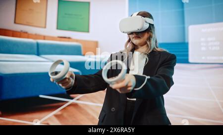 Interior Designer Using a VR Software to Design a Living Space. Change Couch Colors, Move Furniture in Interactive Environment on a Big Digital Screen. Female Engineer Using Headset and Controllers. Stock Photo
