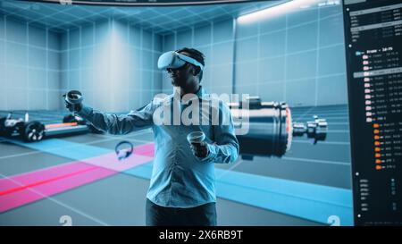 Automotive Engineer Using a VR Software to Showcase Electric Motor and Vehicle Platform in Interactive Environment. Multiethnic Engineer Using Virtual Reality Headset and Controllers for His Project. Stock Photo