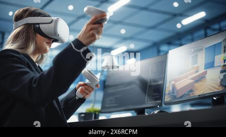 Industrial Software Developer Writing Code and Testing 3D Interior Design Interface. Engineer Editing and Moving Furniture while Wearing Virtual Reality Headset and Using Controllers. Stock Photo