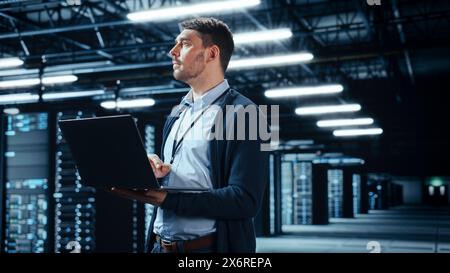 Successful Data Center IT Specialist Using Laptop Computer. Server Farm Cloud Computing Facility with System Administrator Working. Data Protection Engineering Network for Cyber Security. Stock Photo