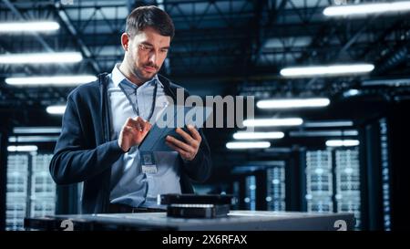 Successful Data Center IT Specialist Using Tablet Computer. Server Farm Cloud Computing Facility with System Administrator Working. Data Protection Engineering Network for Cyber Security. Stock Photo