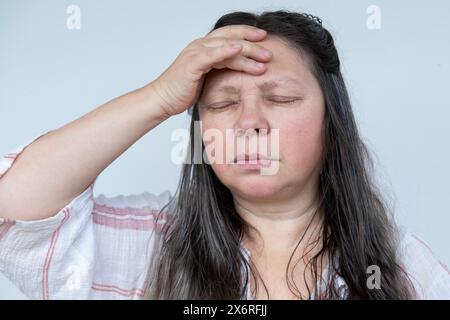 diseased mature woman experiences severe headache, holding head, Hot flashes during menopause, Decreased memory and concentration, feeling nervous, ti Stock Photo