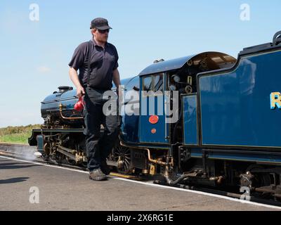 A steam engine driver servicing Samson locomotive on the narrow gauge Romney, Hythe and Dymchurch Railway RH&DR in Dungeness Kent England UK Stock Photo