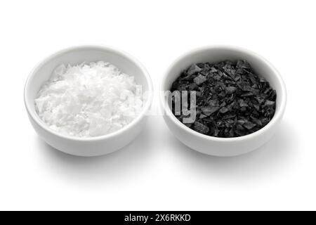 Pair of bowls with black and white sea salt flakes close up isolated on white background Stock Photo