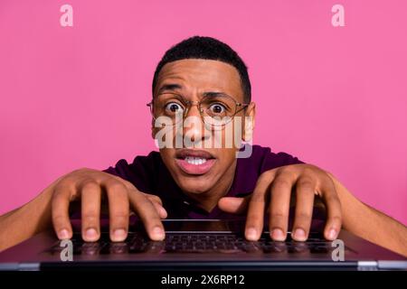 Photo portrait of nice young male typing nervous keyboard computer dressed stylish violet garment isolated on pink color background Stock Photo