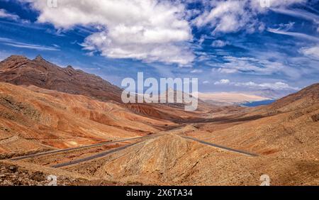 Lonely road through the vast country of Fuerteventura, volcano, dry, barren, horizon, wide sky with clouds Stock Photo