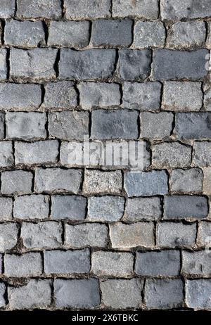 Dark gray cobblestone pavement from old smooth stones as background top view close up Stock Photo