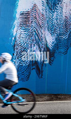 Woman cyclist riding past an urban art installation in Calgary, Alberta Canada Stock Photo