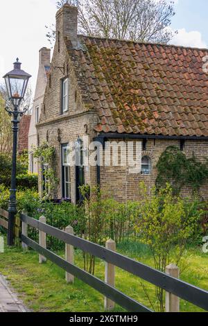 Small brick house with tiled roof and garden, surrounded by fresh spring greenery, rustic atmosphere, historic houses in a small village with small Stock Photo