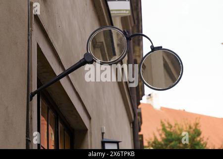 A vintage glasses shop sign featuring a mirrored glasses frame is mounted on the exterior wall of a building, advertising the shops location. The sign Stock Photo