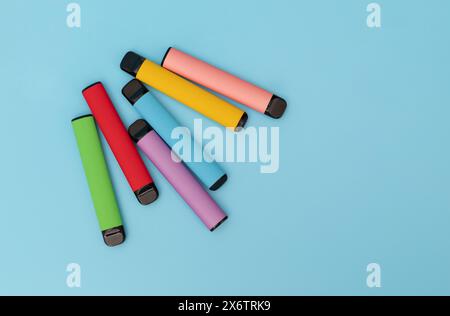 Set of colorful disposable electronic cigarettes on a blue background. The concept of modern smoking Stock Photo