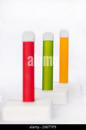 Set of colorful disposable electronic cigarettes on a display stand on a white background. The concept of modern smoking, vaping and nicotine Stock Photo