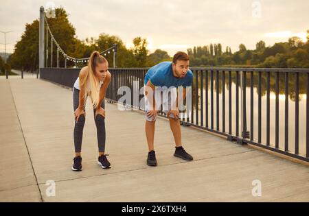 Tired couple in sportswear having a rest after fit sport exercises or jogging outdoors Stock Photo