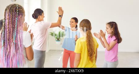 Friendly female choreographer gives high five to her students after successful dance lesson. Stock Photo