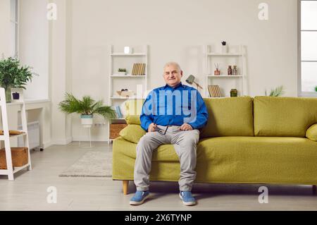 Optimistic elderly man sitting on sofa at home Stock Photo