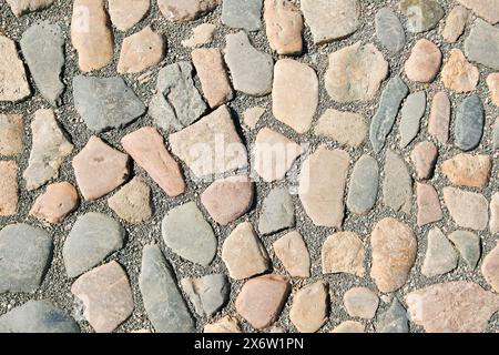 Abstract background of an old cobblestone pavement. Stone pavement texture closeup. Stock Photo