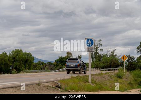 car on the road, on a mountain road. Road with road signs 'use seat belt', sign in Spanish. Safe travel driving Stock Photo