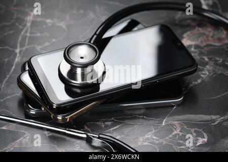 Stack of modern smartphones and stethoscope on black table Stock Photo