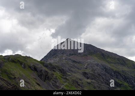 Dramatic landscape of a rugged mountain peak against a backdrop of heavy grey clouds Stock Photo