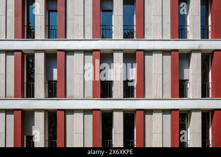 A modern building facade featuring a symmetrical design with alternating vertical stripes in red and beige tones. Stock Photo