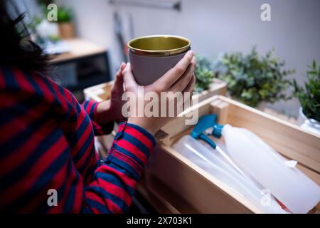 Indonesian teenage girl arranging and planting mini fresh plant in the backyard at home.  Asian female student gardening with joy and responbility to Stock Photo