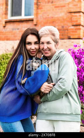 portrait of daughter-in-law hugs mother-in-law and holding dog Stock Photo