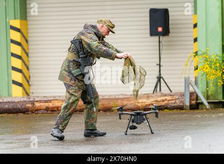 03 May 2024, Rhineland-Palatinate, Kirchheimbolanden: During an exercise, a Bundeswehr soldier shows how an enemy drone is rendered inoperable with a net. The Rhineland-Palatinate State Command is conducting an exercise with the Rhineland-Palatinate and Hunsrück homeland security companies to protect vital defense infrastructure on the site of the former ammunition depot near 'Kriegsfeld' (Donnersberg district). During the Bundeswehr exercise National Guardian, part of the Bundeswehr exercise series QUADRIGA, homeland security forces throughout Germany practise their core mission of protecting Stock Photo