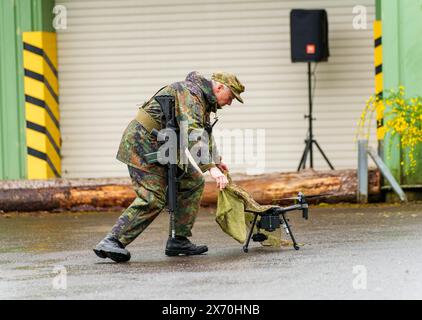 03 May 2024, Rhineland-Palatinate, Kirchheimbolanden: During an exercise, a Bundeswehr soldier shows how an enemy drone is rendered inoperable with a net. The Rhineland-Palatinate State Command is conducting an exercise with the Rhineland-Palatinate and Hunsrück homeland security companies to protect vital defense infrastructure on the site of the former ammunition depot near 'Kriegsfeld' (Donnersberg district). During the Bundeswehr exercise National Guardian, part of the Bundeswehr exercise series QUADRIGA, homeland security forces throughout Germany practise their core mission of protecting Stock Photo