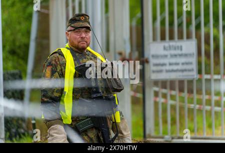 03 May 2024, Rhineland-Palatinate, Kirchheimbolanden: A Bundeswehr soldier secures access to an ammunition depot during an exercise. The Rhineland-Palatinate State Command is conducting an exercise with the Rhineland-Palatinate and Hunsrück homeland security companies to protect vital defense infrastructure on the site of the former ammunition depot near 'Kriegsfeld' (Donnersberg district). During the Bundeswehr exercise National Guardian, part of the Bundeswehr exercise series QUADRIGA, homeland security forces throughout Germany practise their core mission of protecting and securing vital de Stock Photo