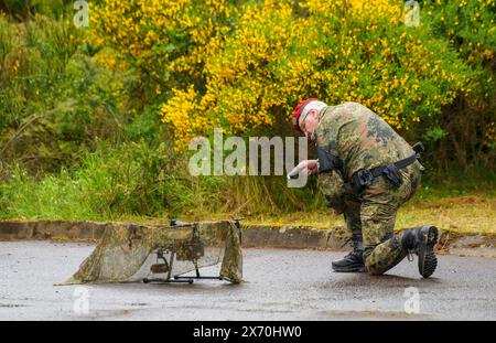 03 May 2024, Rhineland-Palatinate, Kirchheimbolanden: During an exercise, a Bundeswehr soldier examines an enemy drone that has been rendered inoperable with a net. The Rhineland-Palatinate State Command is conducting an exercise with the Rhineland-Palatinate and Hunsrück Homeland Security Companies to protect vital defense infrastructure on the site of the former ammunition depot near 'Kriegsfeld' (Donnersberg district). During the Bundeswehr exercise National Guardian, part of the Bundeswehr exercise series QUADRIGA, homeland security forces throughout Germany practise their core mission of Stock Photo