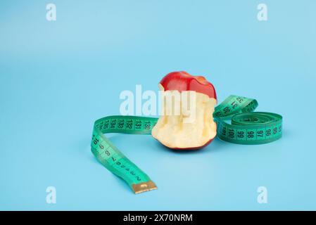 Red bitten apple and measuring tape on a blue background with copy space Stock Photo