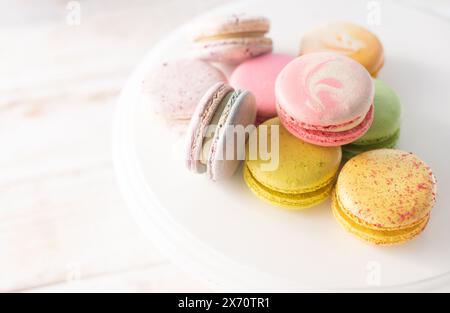 Multi-colored macarons close up on wood background with soft lights. Delicate French dessert for breakfast in the morning light. Stock Photo