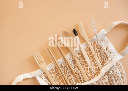 Eco friendly bag and bamboo cutlery set with toothbrush on beige background for green life and zero waste concept. Top view. Stock Photo