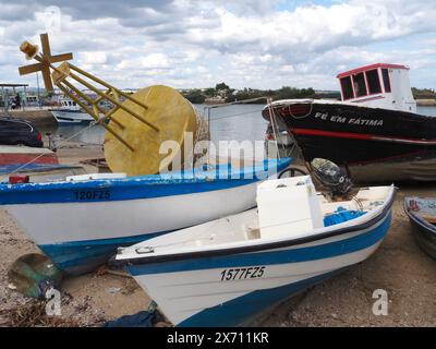 Small pleasure craft with yellow concrete land marker buoy in the harbour, Fuseta (Fuzeta), the Algarve southern Portugal. Stock Photo