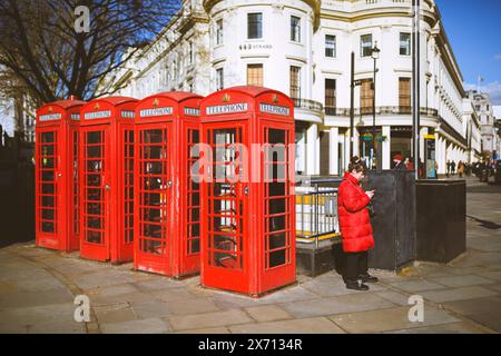 London Calling. 4 telephones at Charing Cross in London and a lady with a mobile phone. Stock Photo