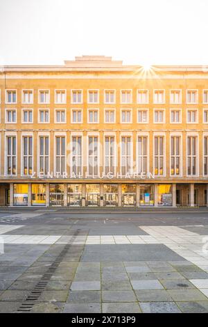 Sunlight flares above the historic Tempelhof Airport terminal in Berlin, casting a warm glow on its facade. Stock Photo