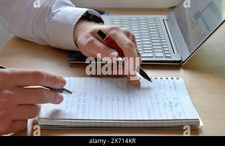 Business meeting with laptop and two hands over a notepad in office Stock Photo