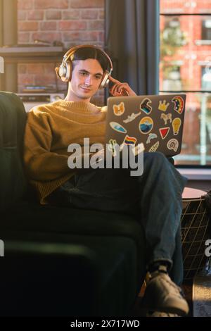 Vertical Screen: Young Handsome Man Working from Home on Laptop Computer in Stylish Loft Apartment During the Day. Creative Person Checking Social Media, Browsing Internet. Stock Photo