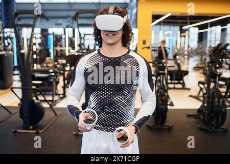 Waist up portrait of smiling man wearing VR headset in gym enjoying immersive experience copy space Stock Photo