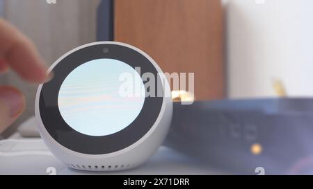 Paris, France - Jun 5th, 2020: POV - A hand reaches to interact with the Amazon Echo Spot, featuring a circular display in the setup phase Stock Photo