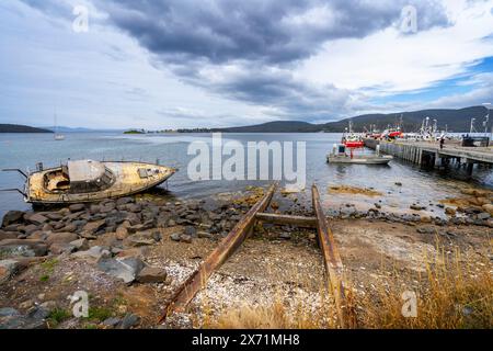 Abandoned yacht washed up on rocky shoreline, Dover public jetty, Dover Tasmania Stock Photo