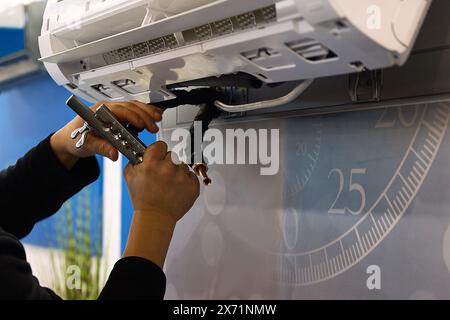 Technician man worker installs air conditioner Stock Photo