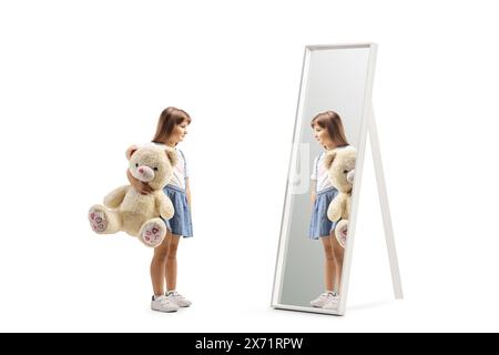 Girl holding a big teddy bear and looking at a mirror isolated on white background Stock Photo