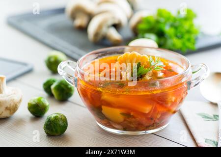 vegetable soup with Brussels sprouts and cauliflower, in a glass plate on a wooden table Stock Photo